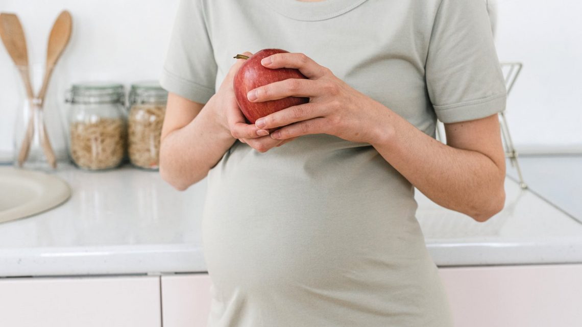 crop pregnant woman with apple